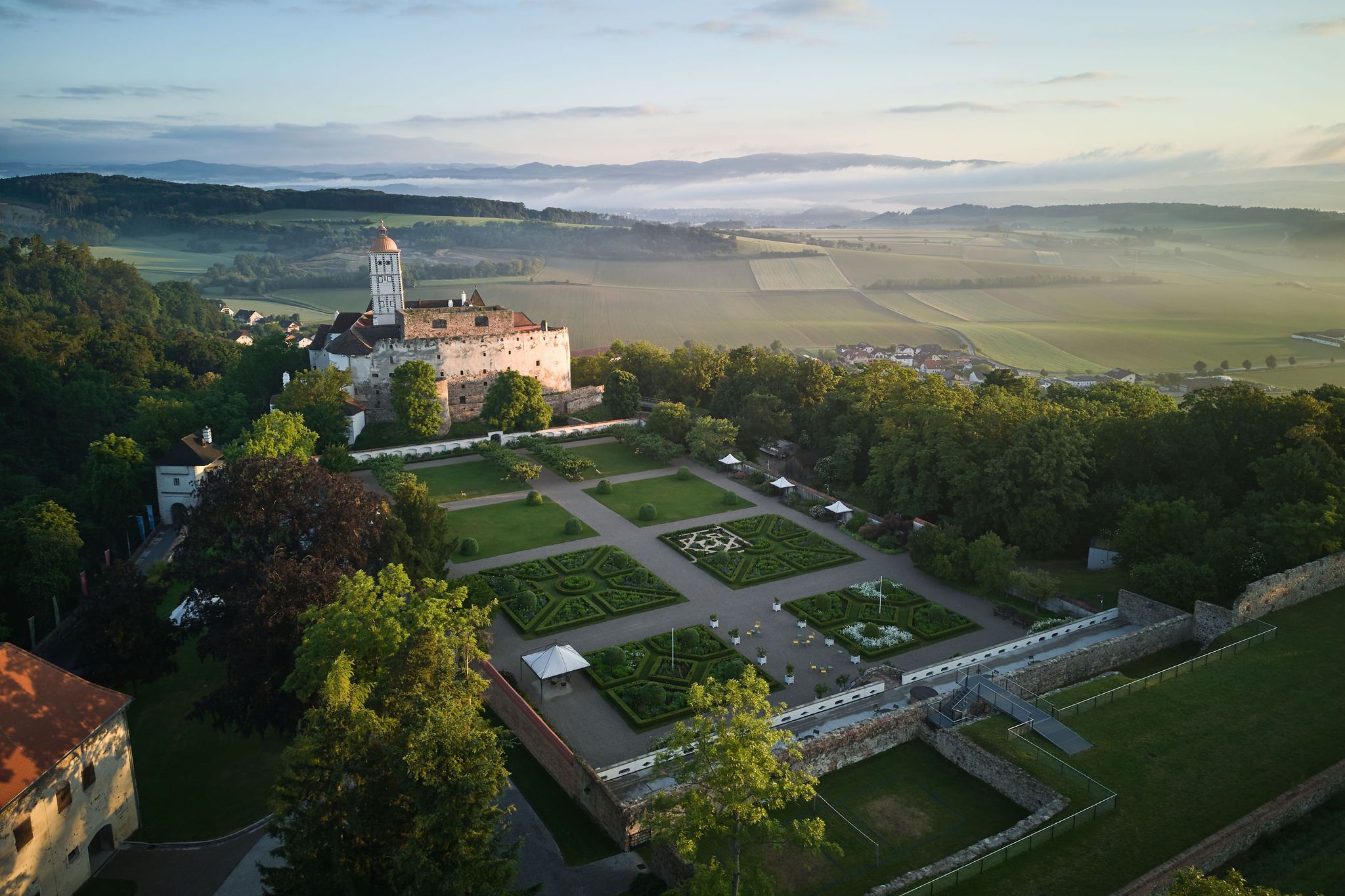 Luftaufnahme der Schallaburg mit Gartenanlage und umliegender Landschaft.