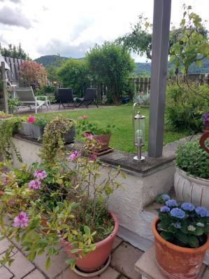 Garten mit Blumen und Sitzbereich im Hintergrund.
