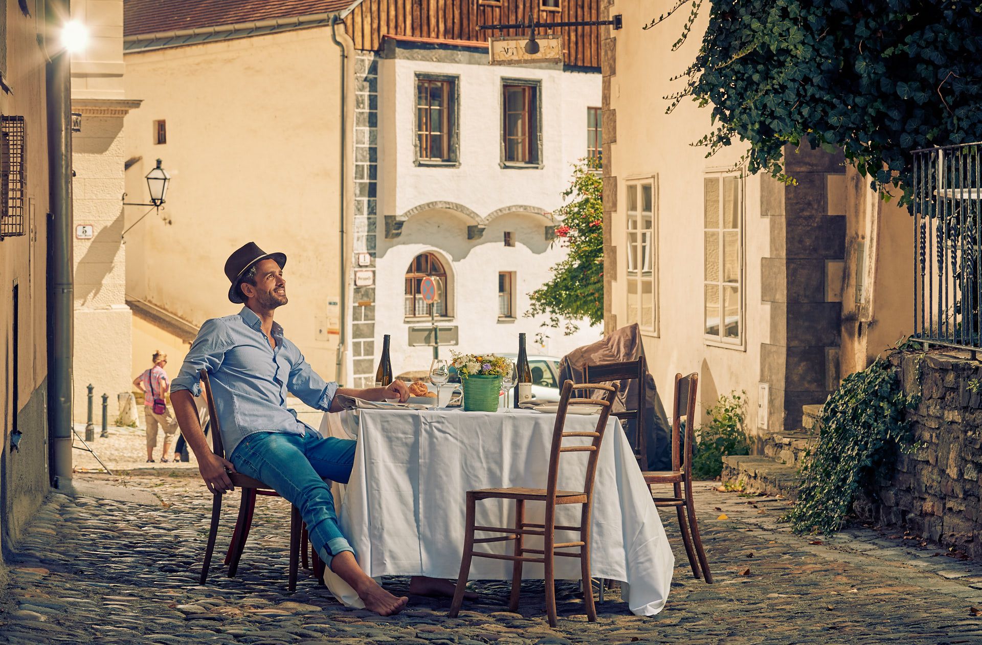 Mann sitzt an einem Tisch in einer gepflasterten Gasse der Altstadt von Krems.