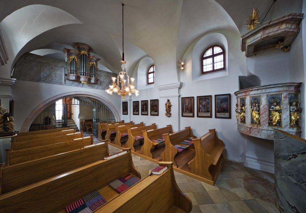 Innenansicht einer kleinen Kirche mit Holzbänken, einer Kanzel und einer Orgel auf der Empore.