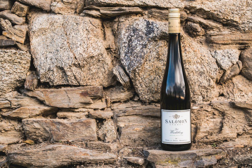 Weinflasche vor einer Steinmauer.