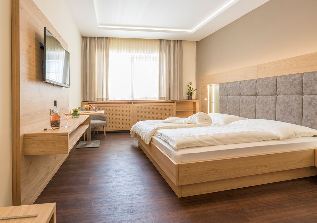 Modernes Gästezimmer mit Doppelbett, Flachbildfernseher und Holzmöbeln.