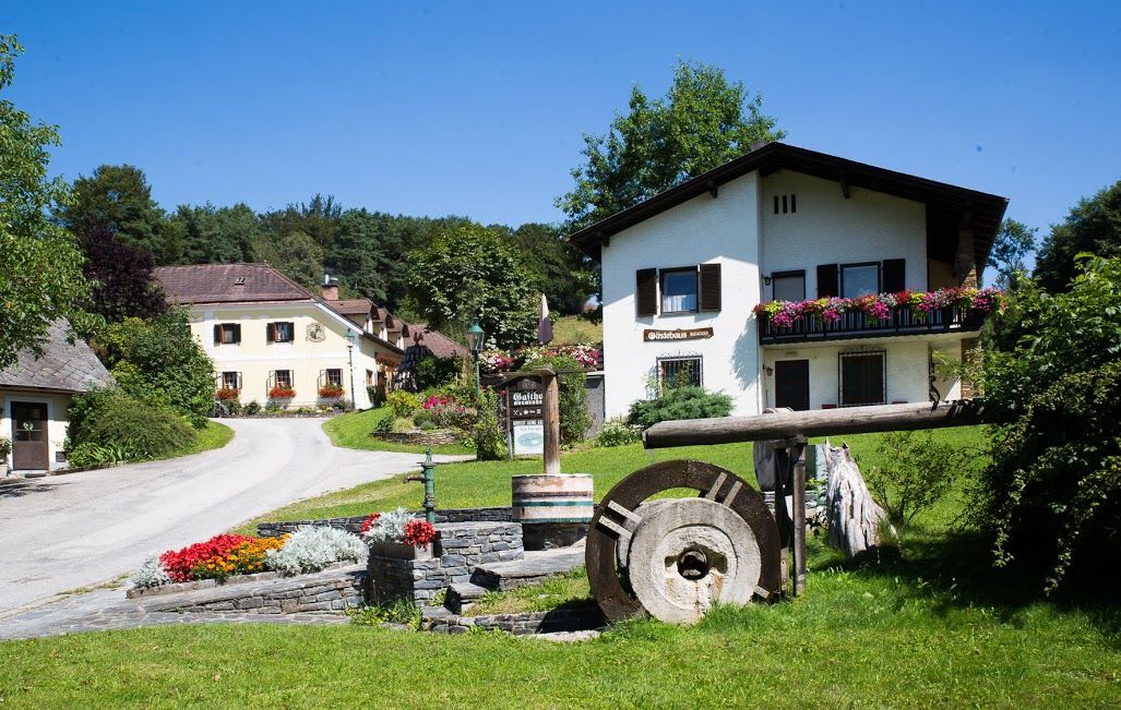 Ein ländliches Gästehaus mit Blumen und einem alten Mühlstein im Vordergrund.