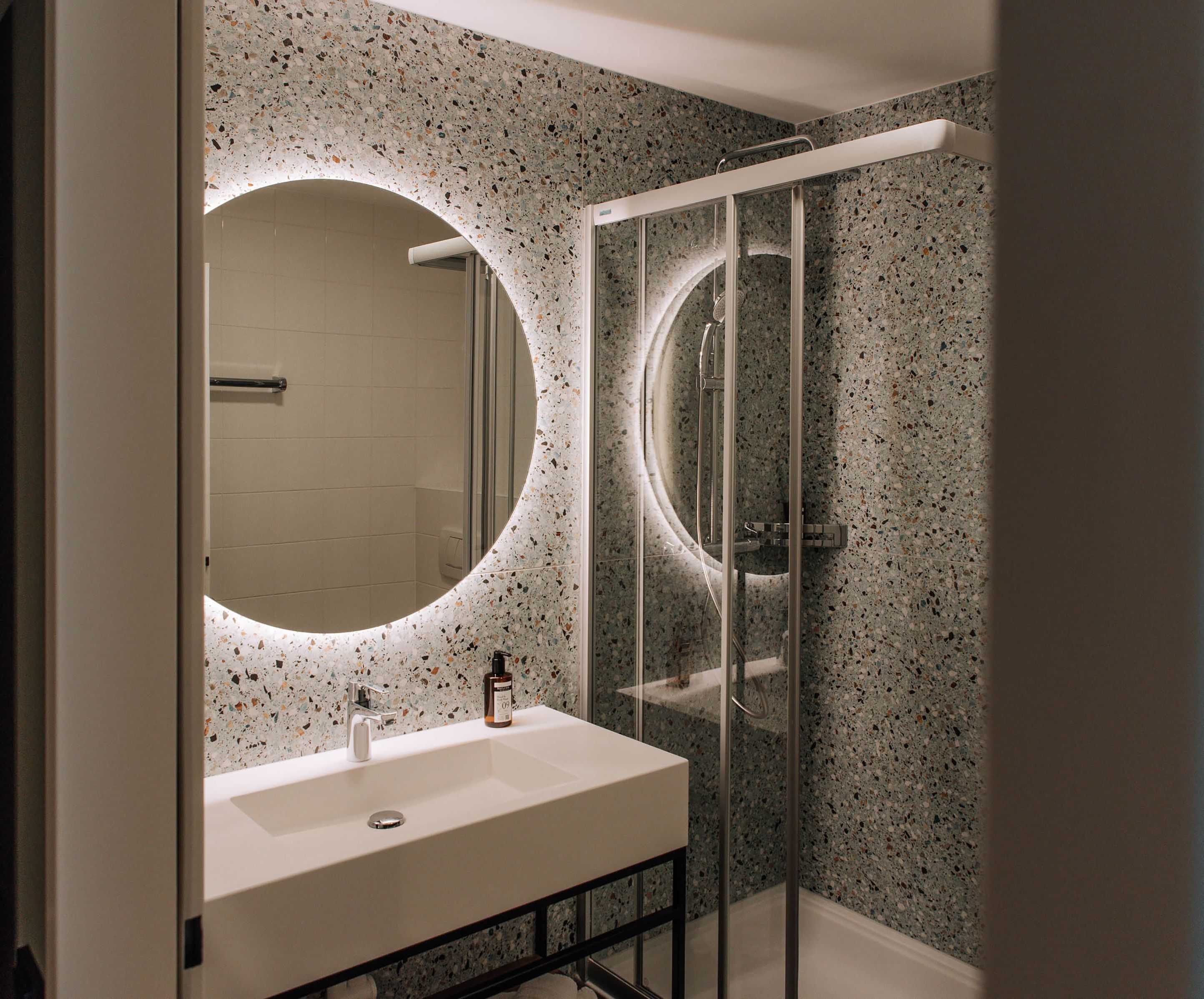 Modernes Badezimmer mit beleuchtetem Spiegel und Dusche.