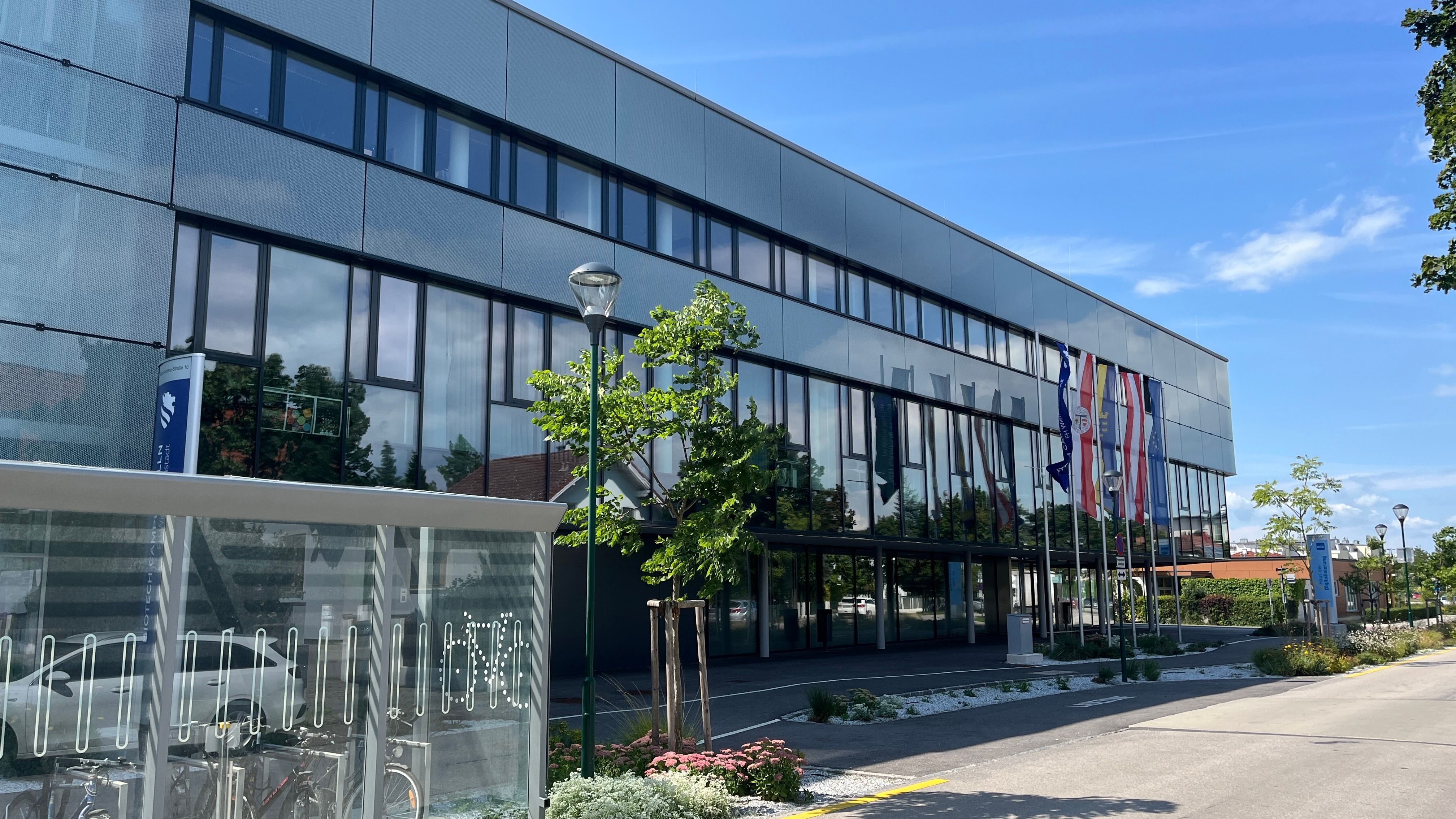 Modernes Gebäude mit Glasfassade und E-Bike-Ladestation im Vordergrund.