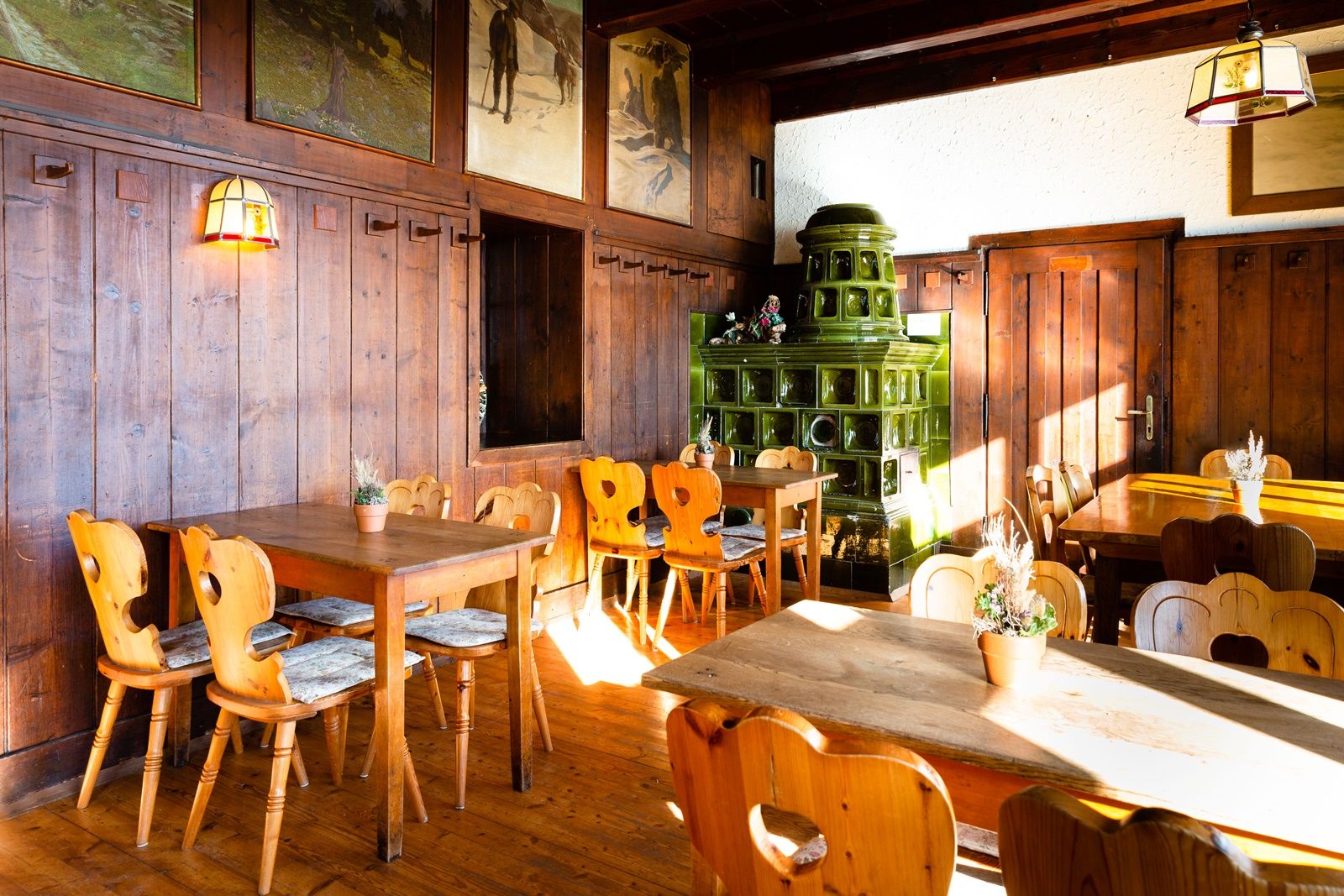 Gemütliche Gaststube mit Holzmöbeln und grünem Kachelofen.