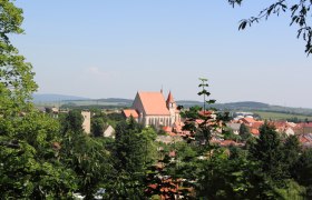 Panoramablick auf Eggenburg mit Kirche und umliegenden Gebäuden, umgeben von Bäumen und Hügeln im Hintergrund.