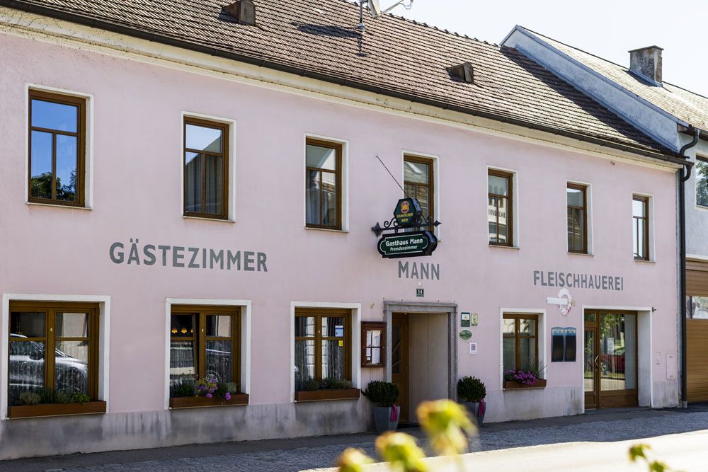Gasthaus mit Gästezimmern in rosa Gebäude.