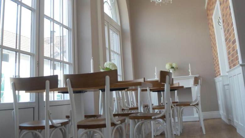 Eleganter Raum mit hohen Fenstern, Kronleuchtern und Holzm&ouml;beln.