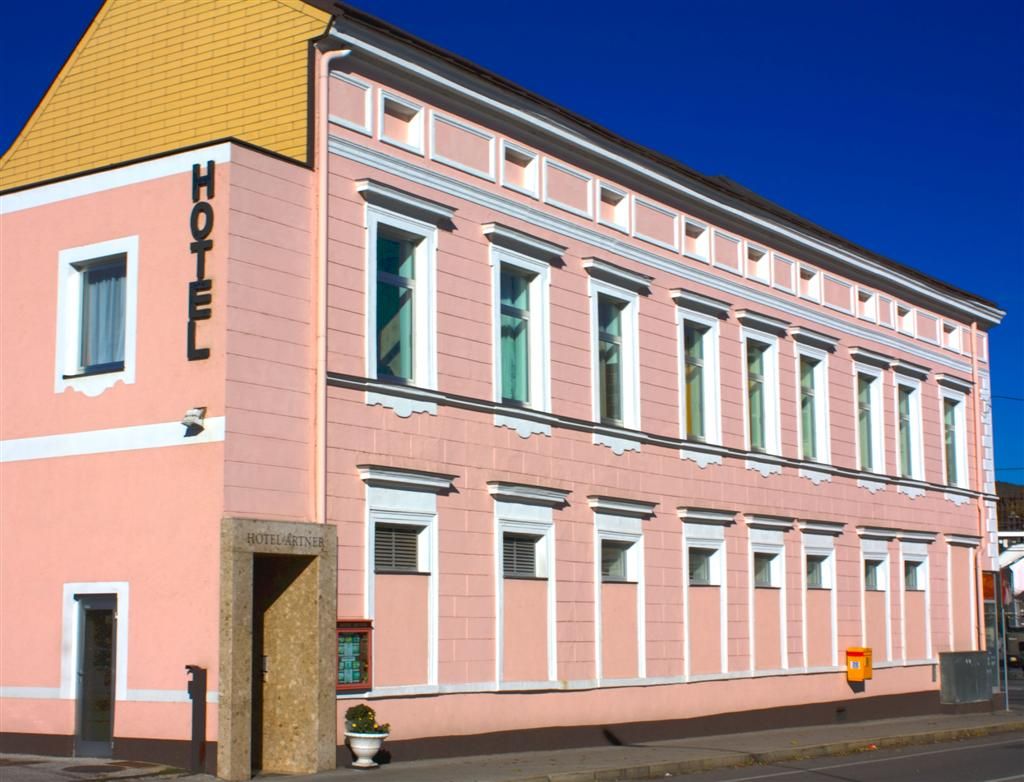 Ein rosa Gebäude mit der Aufschrift 'Hotel' an der Fassade.