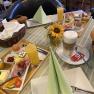 Ein gedeckter Frühstückstisch mit Brötchen, Aufschnitt, Eiern, Saft und Kaffee in einer Pension.
