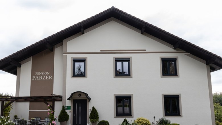 Au&szlig;enansicht der Pension Parzer mit Garten und Terrasse.