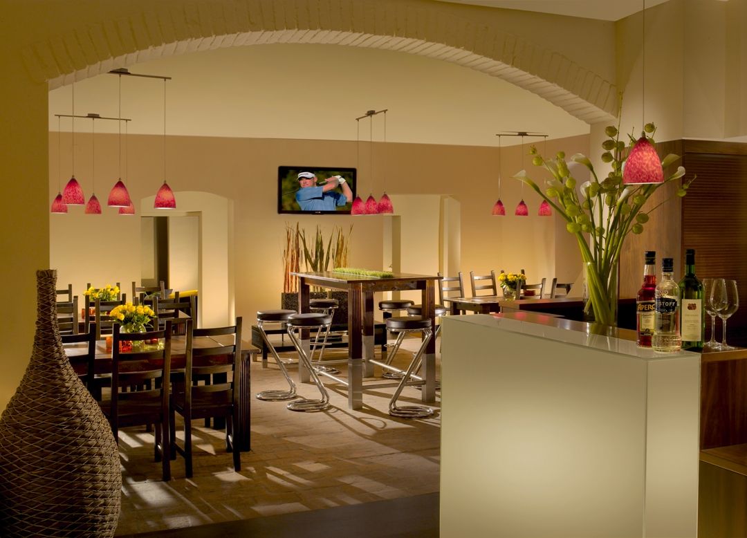 Innenansicht eines stilvollen Restaurants mit modernen Möbeln und roten Hängelampen.