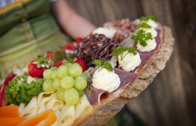 Eine rustikale Platte mit K&auml;se, Schinken, Trauben, Erdbeeren und Kr&auml;utern.