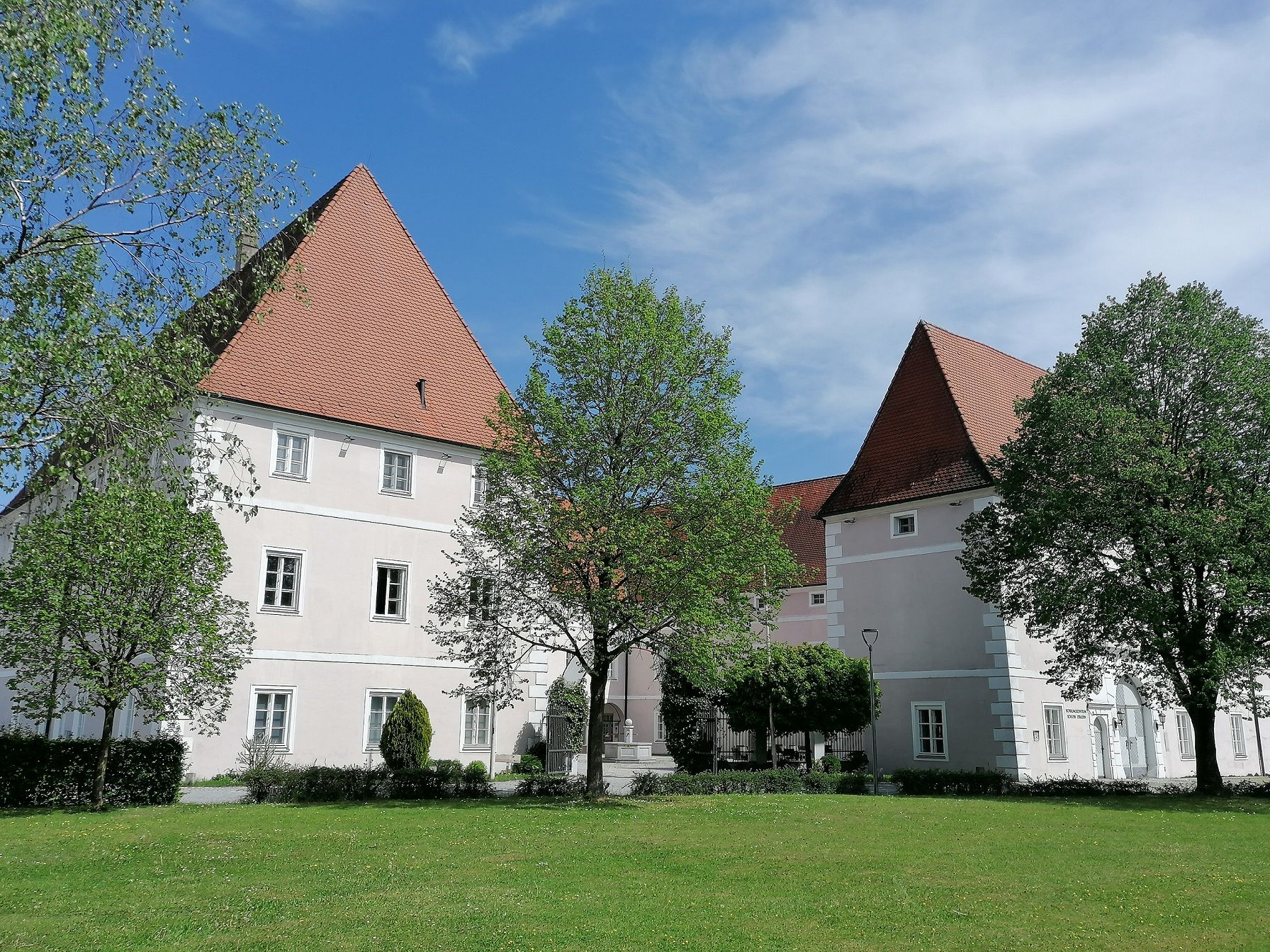 Schloss Hotel Zeillern mit grüner Wiese und Bäumen im Vordergrund.