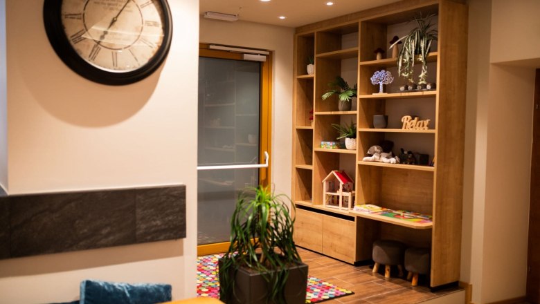 Innenansicht eines Bistros mit gro&szlig;er dekorativer Uhr, Regal und Kinderspielecke.