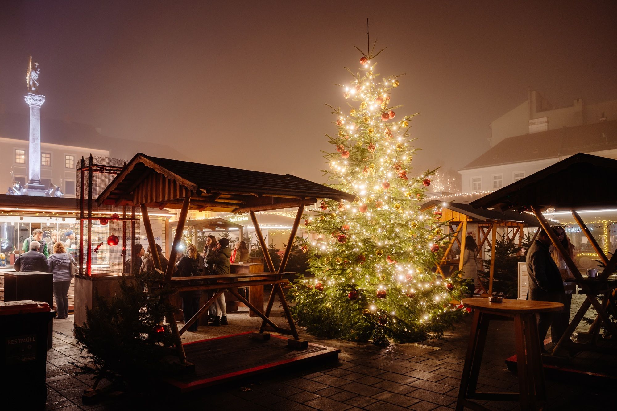 Hell erleuchteter Weihnachtsbaum mit Marktständen in der Wiener Neustädter Innenstadt