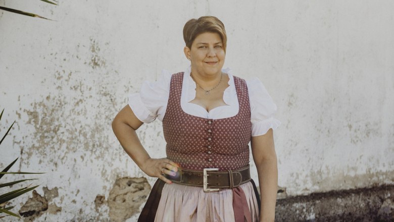 Frau in traditioneller Tracht vor einer wei&szlig;en Wand.