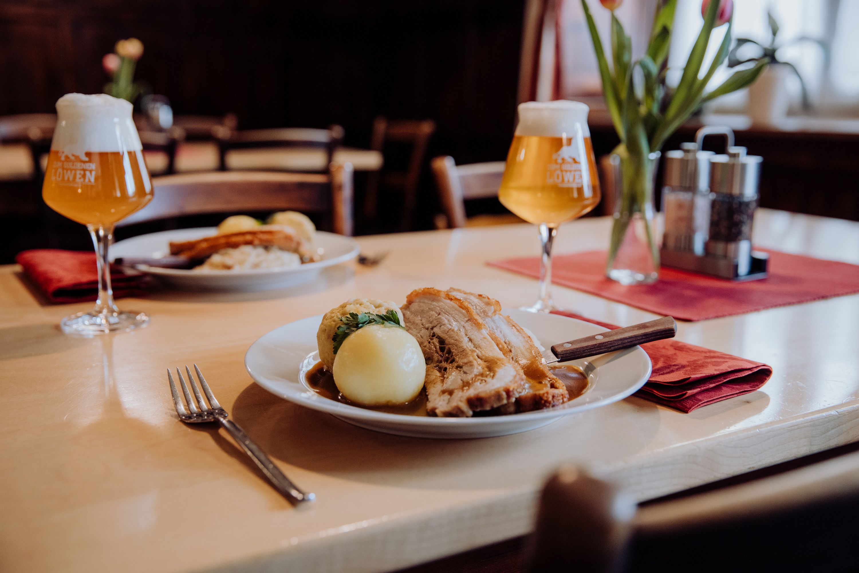 Schweinsbraten mit Knödel und Bier in einem gemütlichen Restaurant.