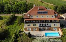 Luftaufnahme eines großen Hauses mit Pool und Solarpanelen, umgeben von Weinbergen.