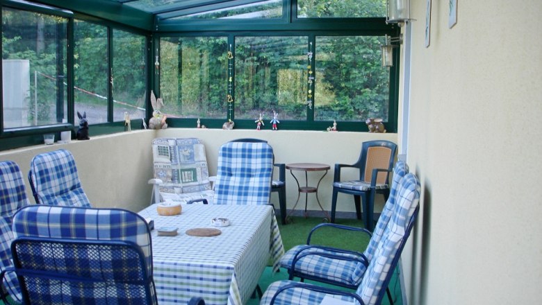 Wintergarten mit Tisch und St&uuml;hlen, dekoriert mit Figuren.