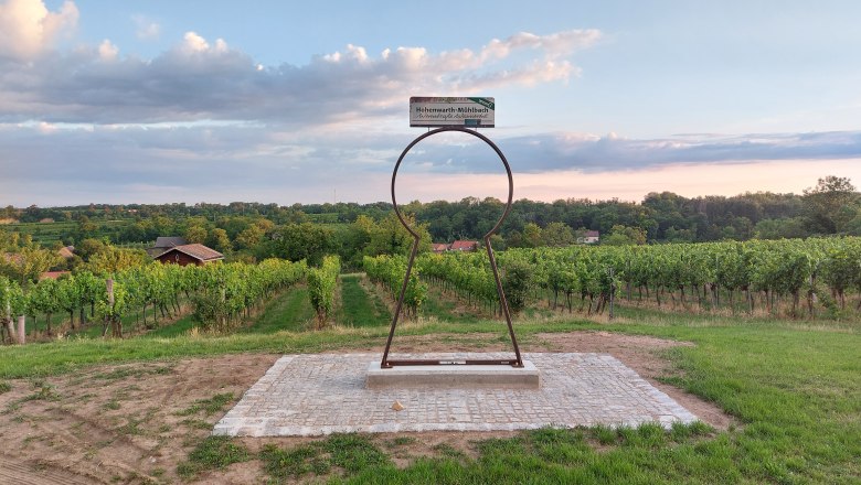 Ein Schl&uuml;ssellochrahmen mit Blick auf Weinberge und einen bew&ouml;lkten Himmel.