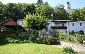 Au&szlig;enansicht eines Hauses mit Garten und B&auml;umen im Hintergrund.