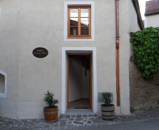 Offene Haust&uuml;r eines historischen Geb&auml;udes mit zwei Blumentr&ouml;gen links und rechts