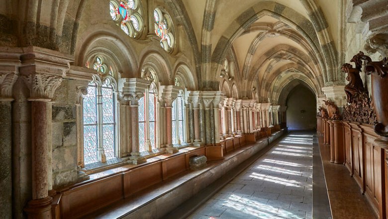 Ein gotischer Kreuzgang im Stift Zwettl mit bunten Glasfenstern und steinernen B&ouml;gen.