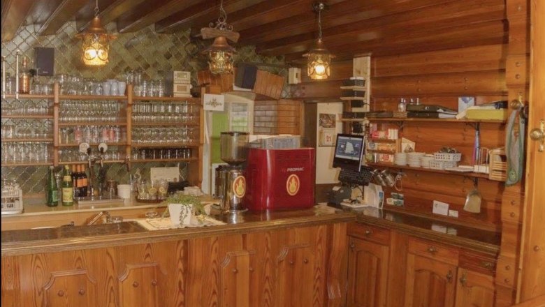 Rustikaler Schankbereich mit Holzmöbeln und Gläsern.