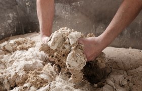 H&auml;nde kneten Teig in einer gro&szlig;en Sch&uuml;ssel.