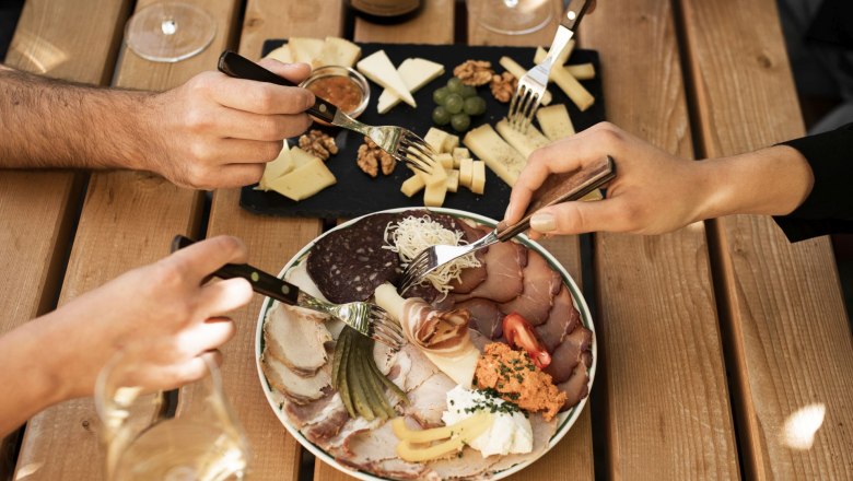 Ein Tisch mit Weinflasche, Gläsern, Käseplatte und Aufschnitt.