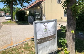 Ein Schild vor einem Geb&auml;ude mit der Aufschrift 'Mittagsbuffet' und 'Herzlich Willkommen bei Familie Rauscher'.