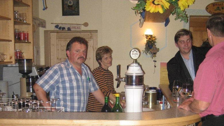 Innenansicht eines Heurigen mit Menschen an der Bar.