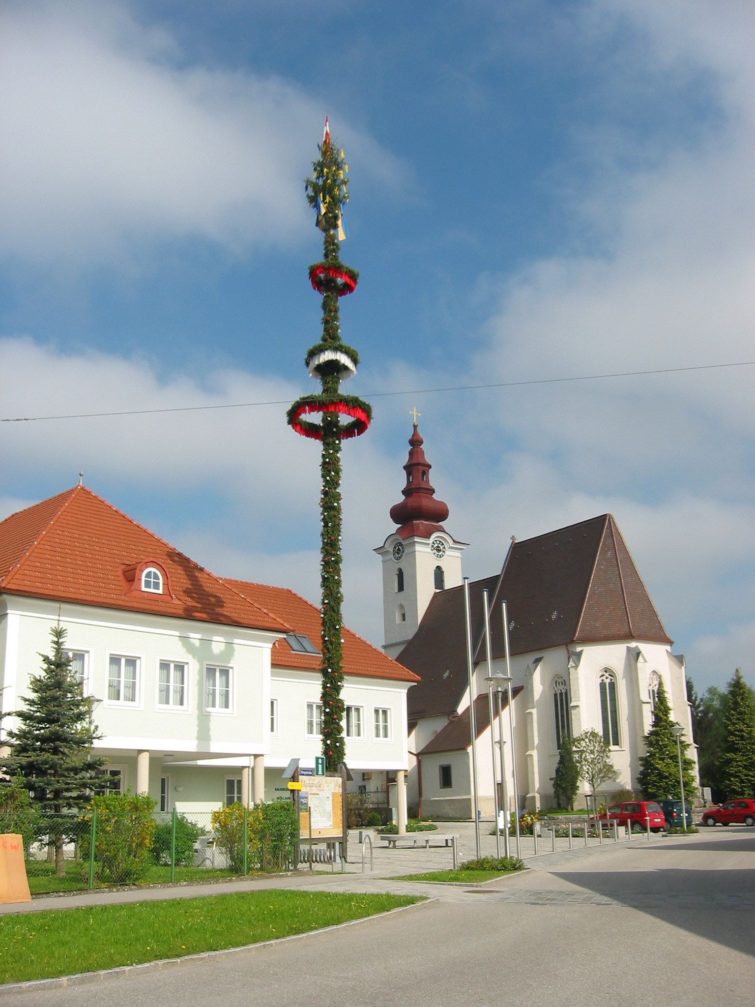 Kirche mit Zwiebelturm und Maibaum in St. Pantaleon-Erla.