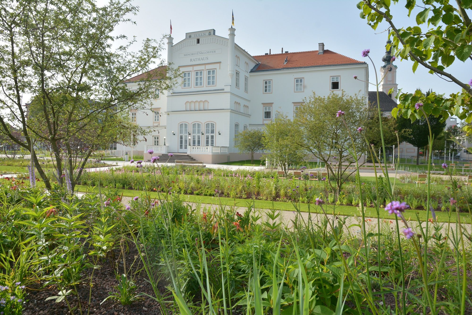 Das Minoritenkloster in Tulln mit gepflegtem Garten im Vordergrund.