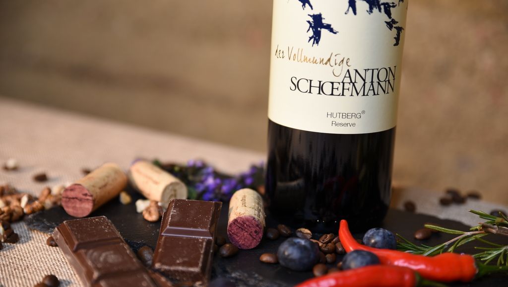 Weinflasche mit Schokolade, Korken und Gewürzen auf einem Tisch.