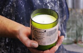 Eine Hand h&auml;lt eine gr&uuml;ne Duftkerze mit Etikett 'Weinviertler Kerzen'.