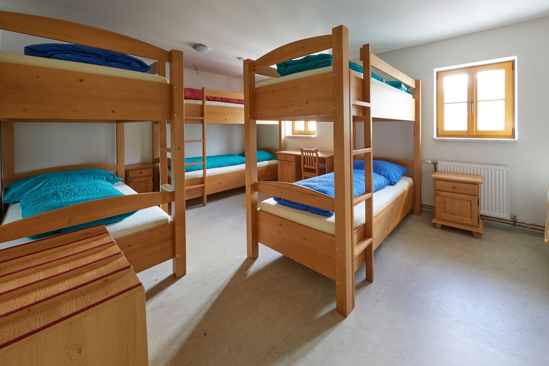 Mehrbettzimmer mit Etagenbetten und Holzmöbeln.