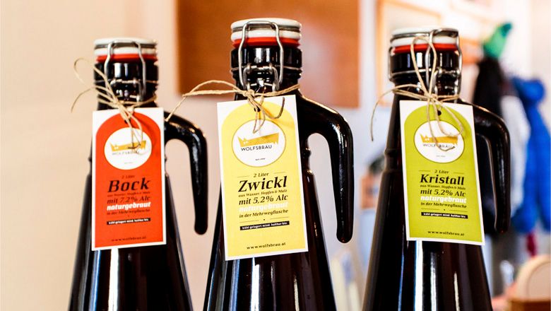 Drei Bierflaschen mit Etiketten von Wolfsbräu: Bock, Zwickl und Kristall.