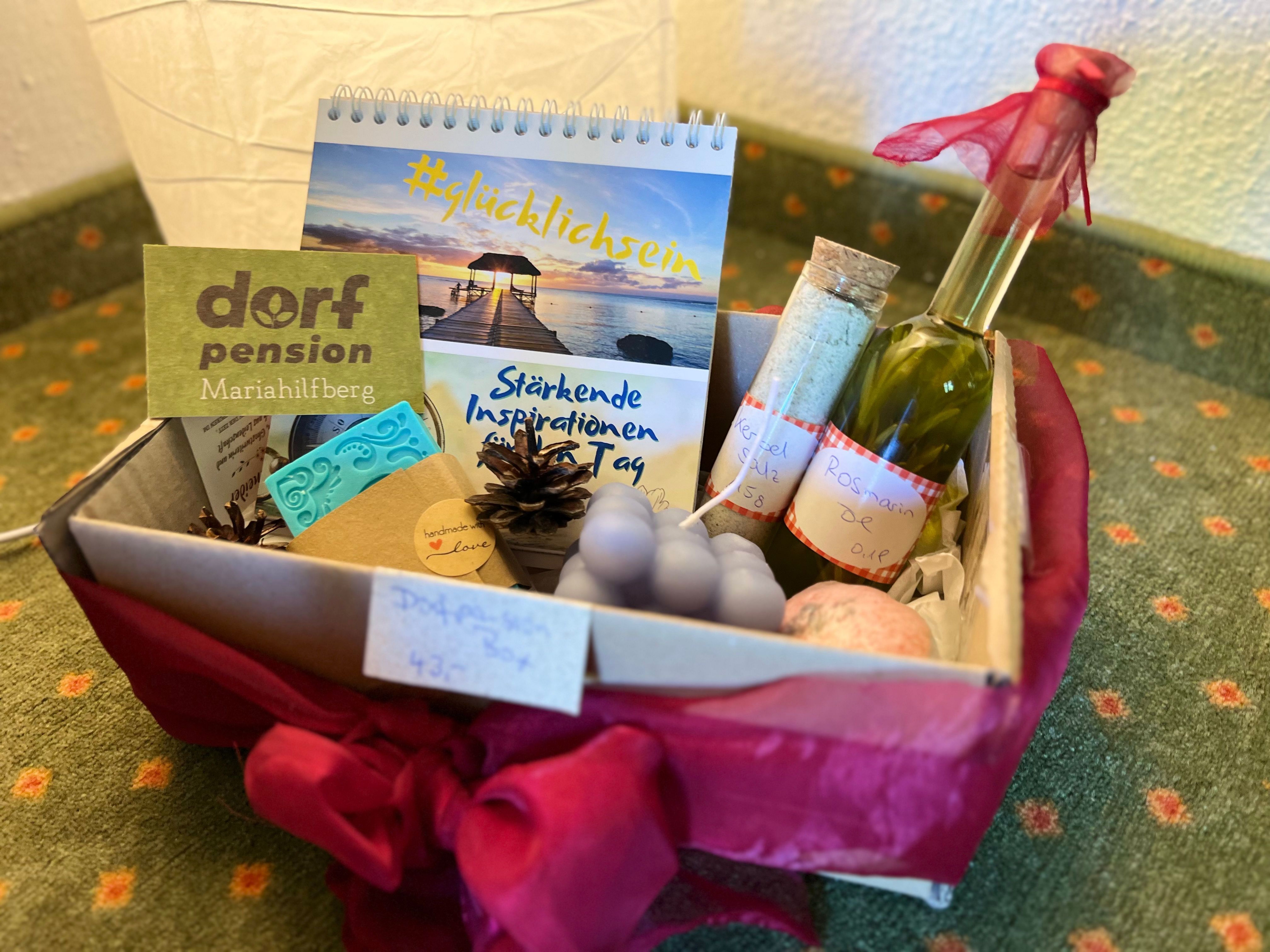 Ein Geschenkkorb mit verschiedenen Wellness-Produkten, darunter ein Kalender, eine Flasche Öl und handgemachte Seifen.
