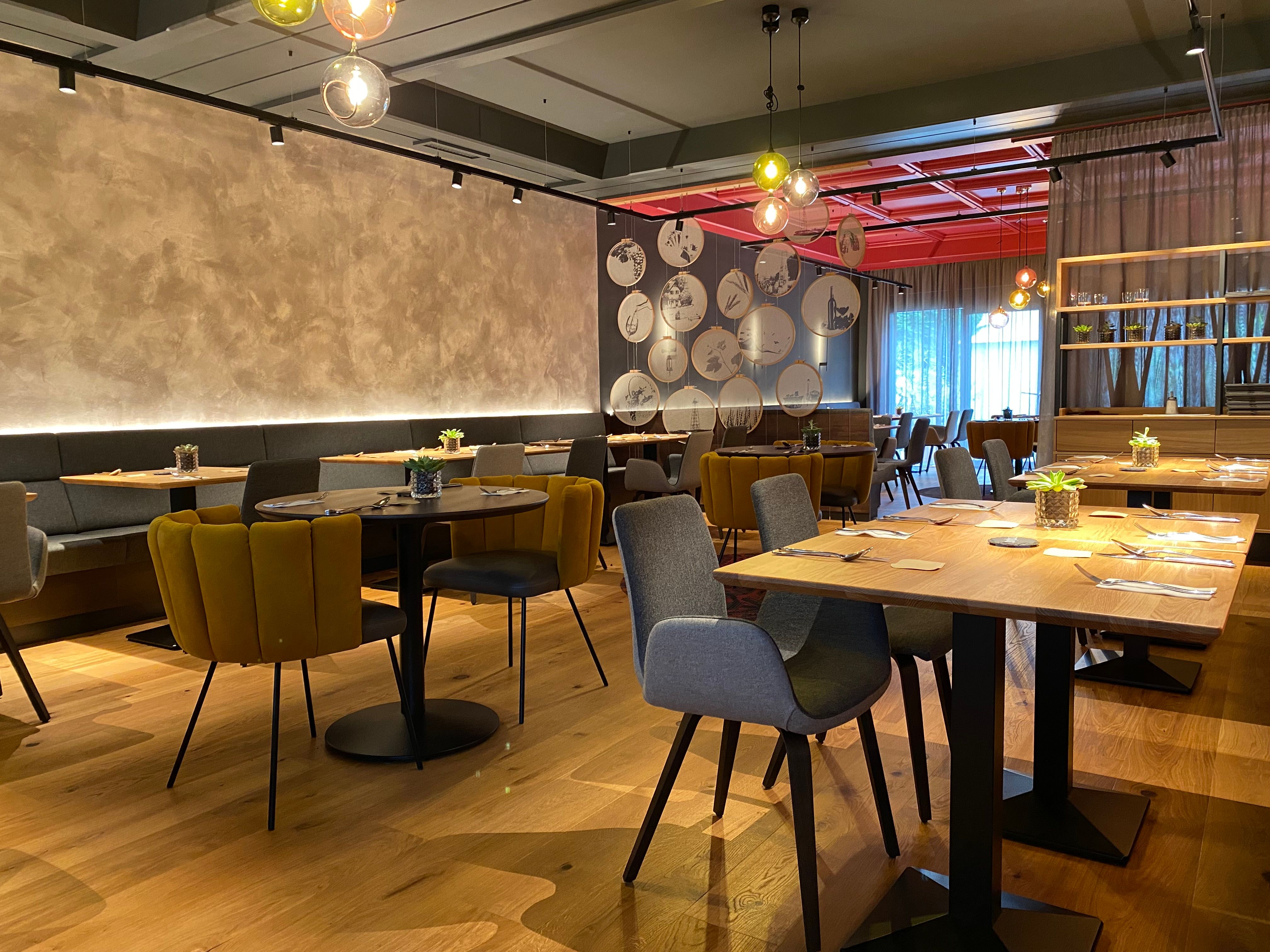 Modernes Restaurant mit stilvoller Einrichtung, Holztischen und gemütlichen Stühlen.