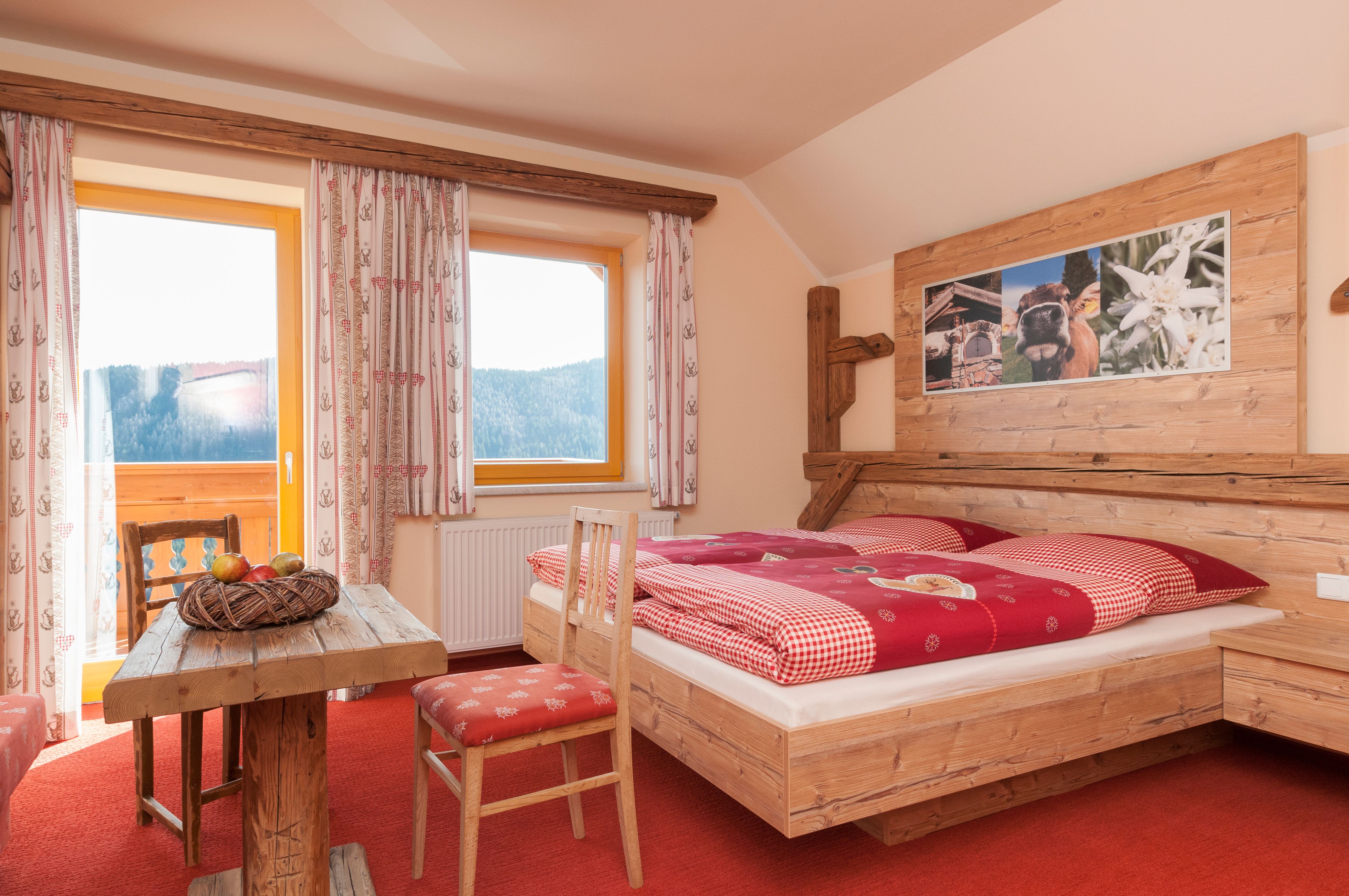 Gemütliches Zimmer im Alpenstil mit Holzmöbeln, rotem Teppich und Bergblick.
