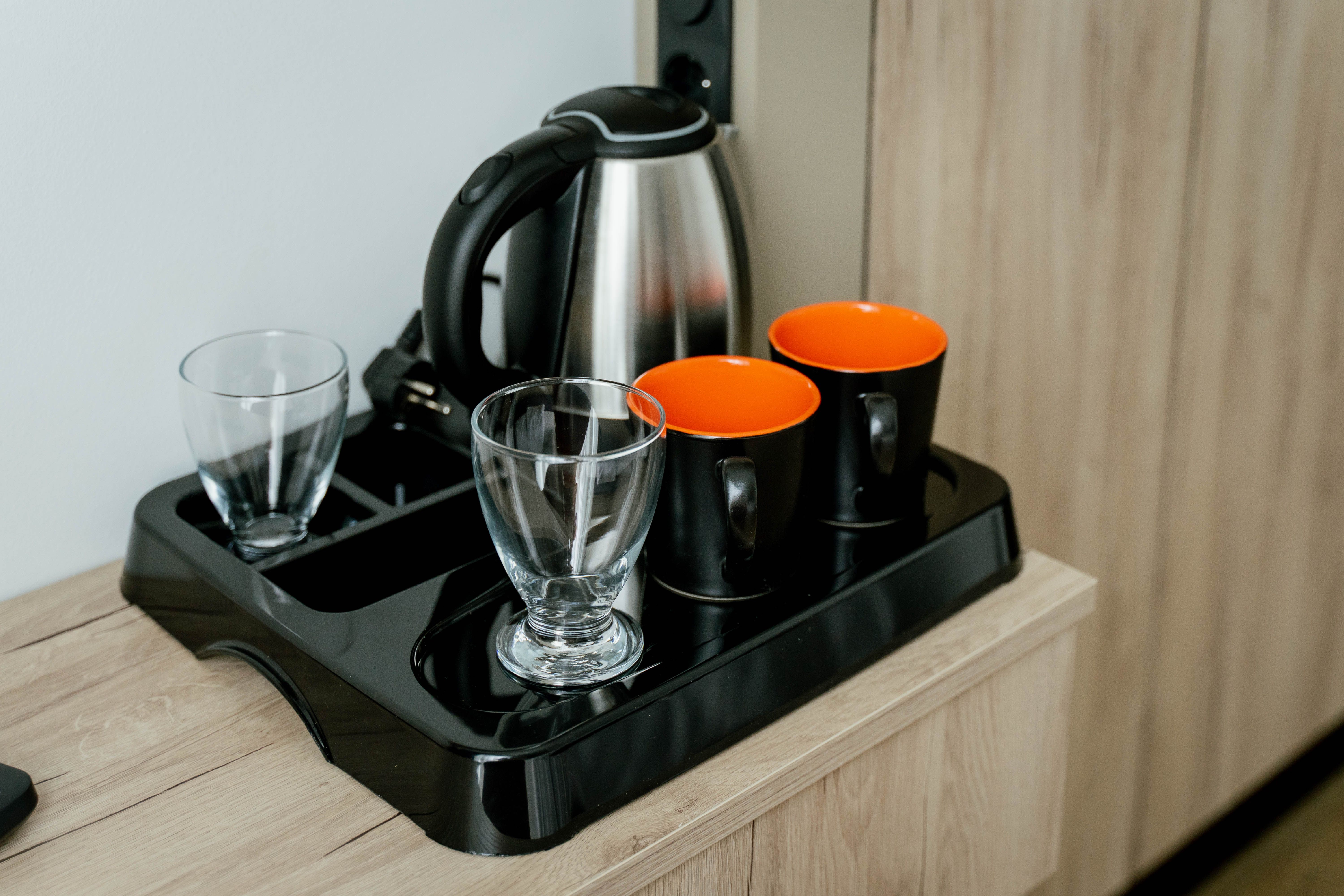 Tablett mit Wasserkocher, zwei Gläsern und zwei Tassen.