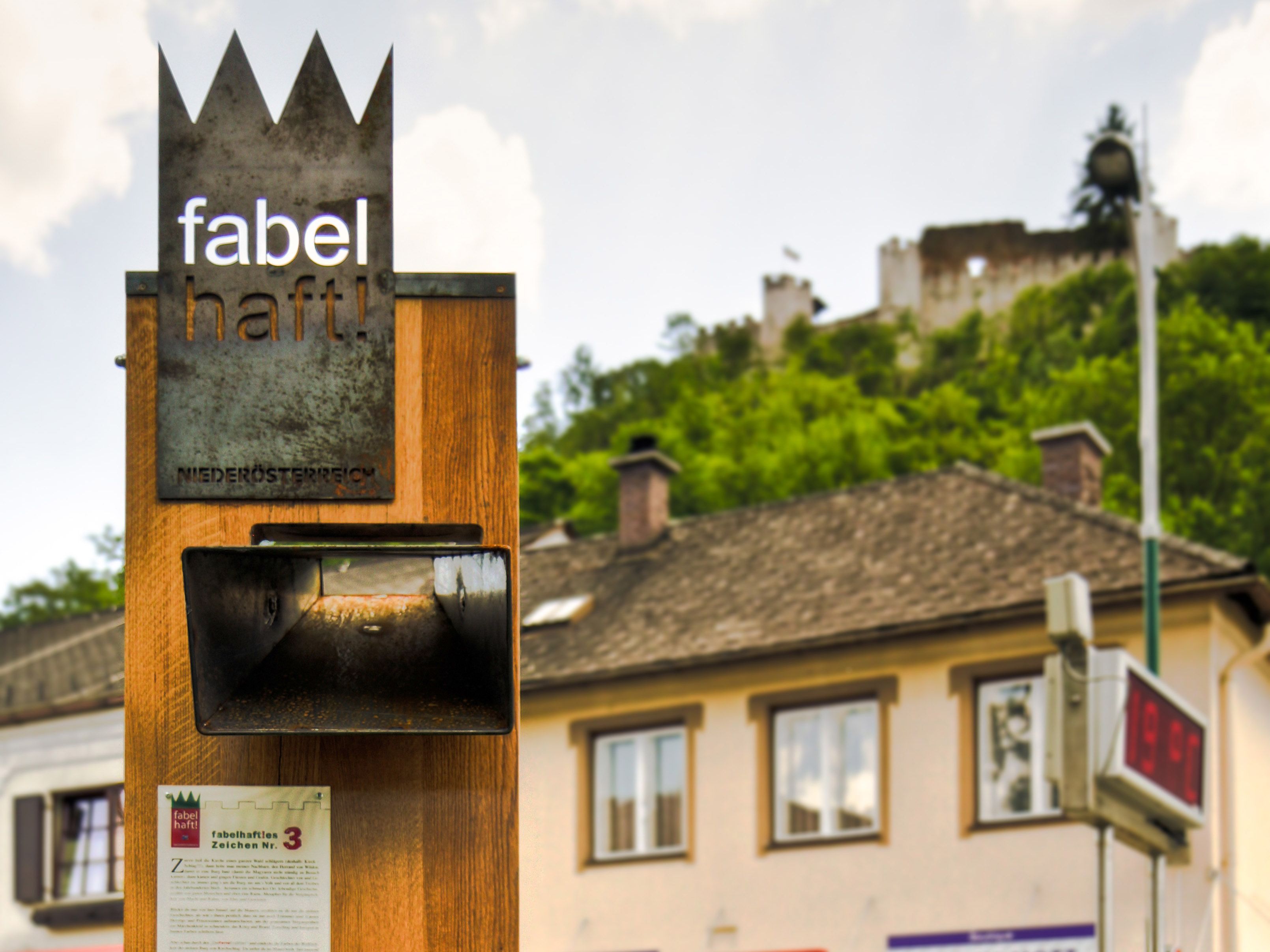 Ein Schild mit der Aufschrift 'fabelhaft!' vor einer Burgruine in Niederösterreich.