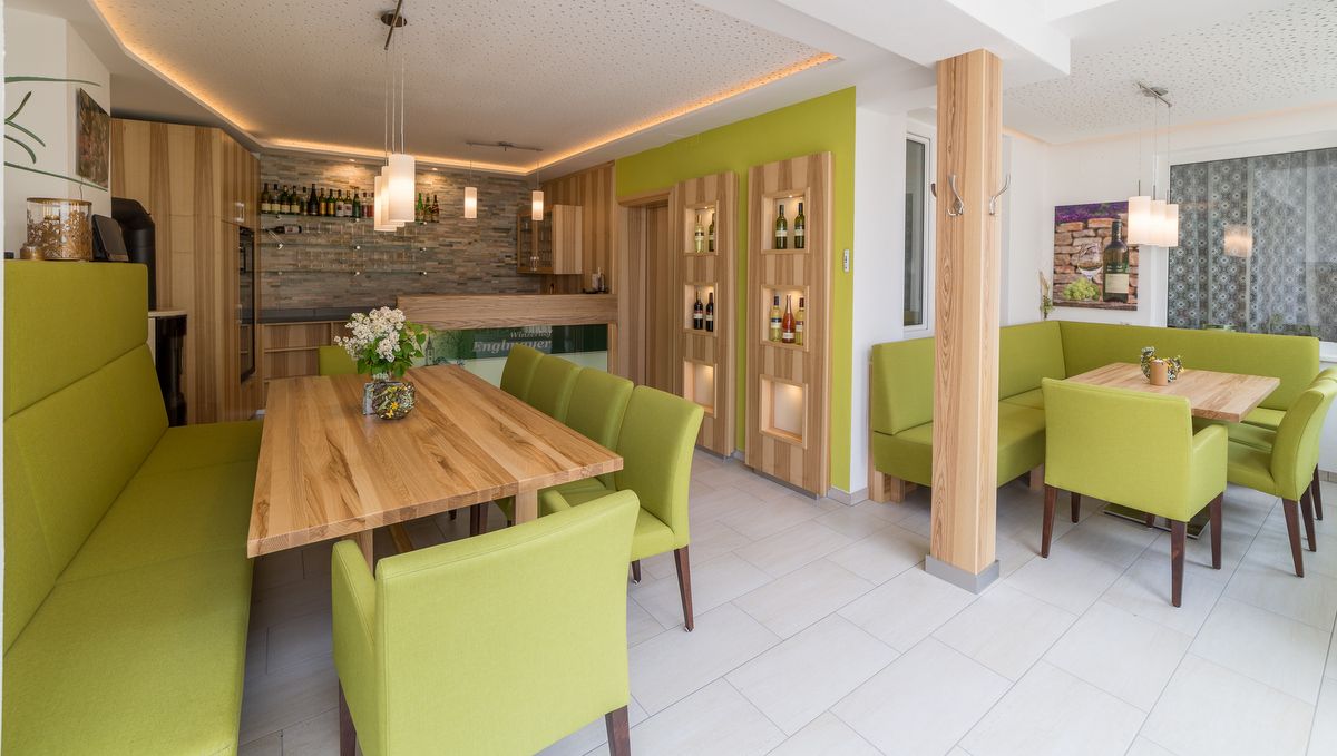 Moderner Verkostungsraum mit Holztischen und grünen Polstermöbeln.