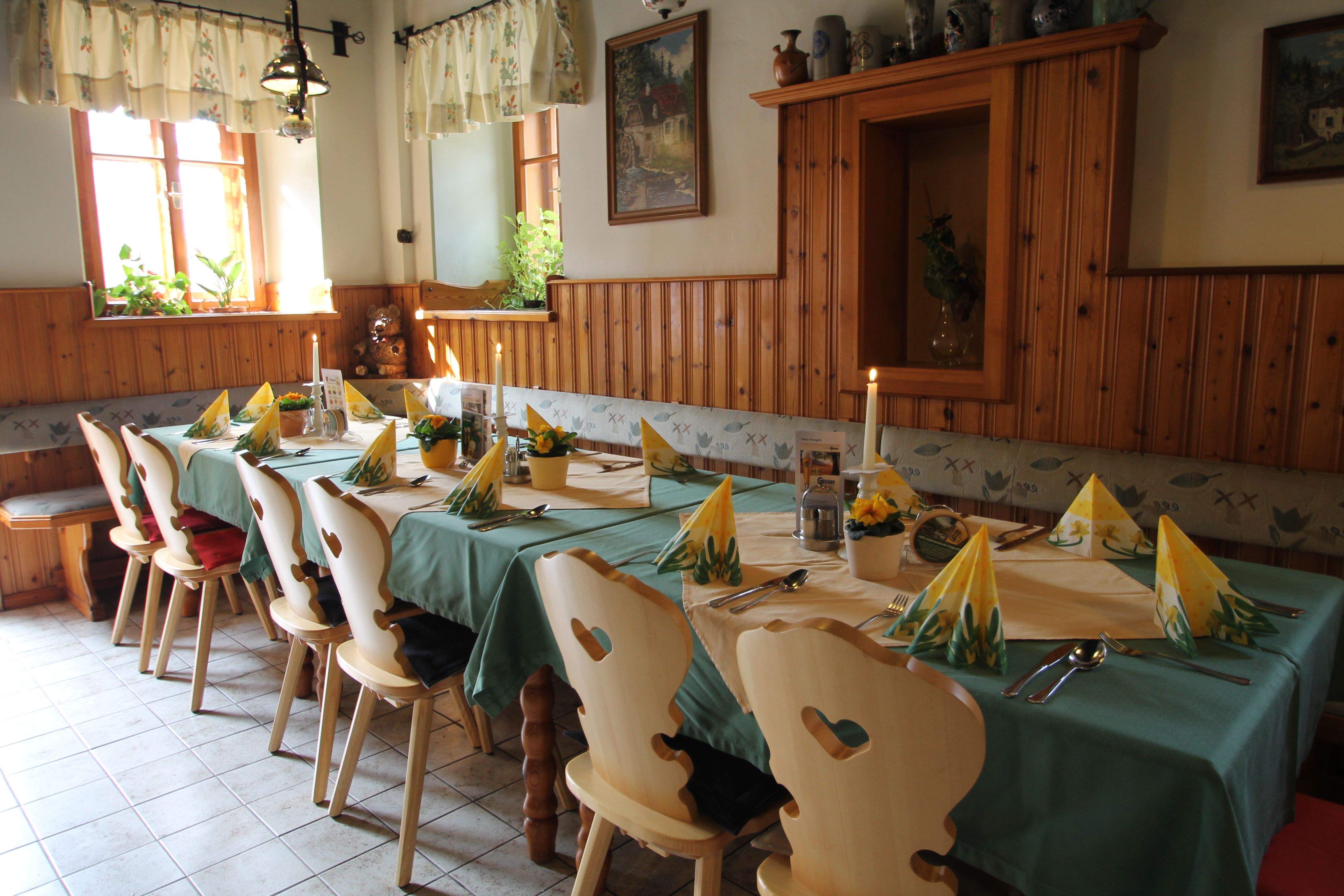 Gemütliche Gaststube mit gedecktem Tisch, Holzstühlen und Dekoration.