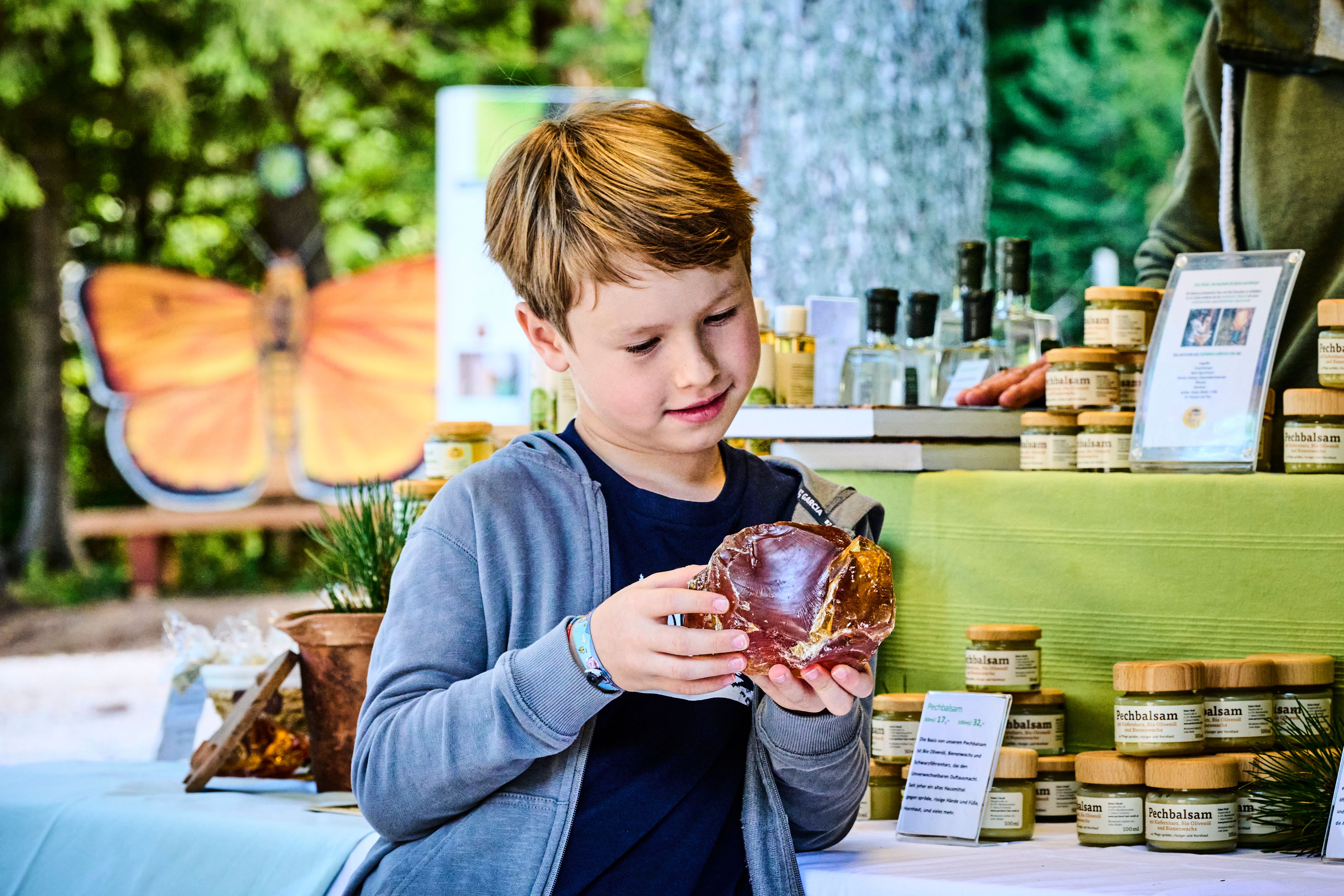 Ein Junge betrachtet ein großes Stück Harz auf einem Marktstand mit Naturprodukten.