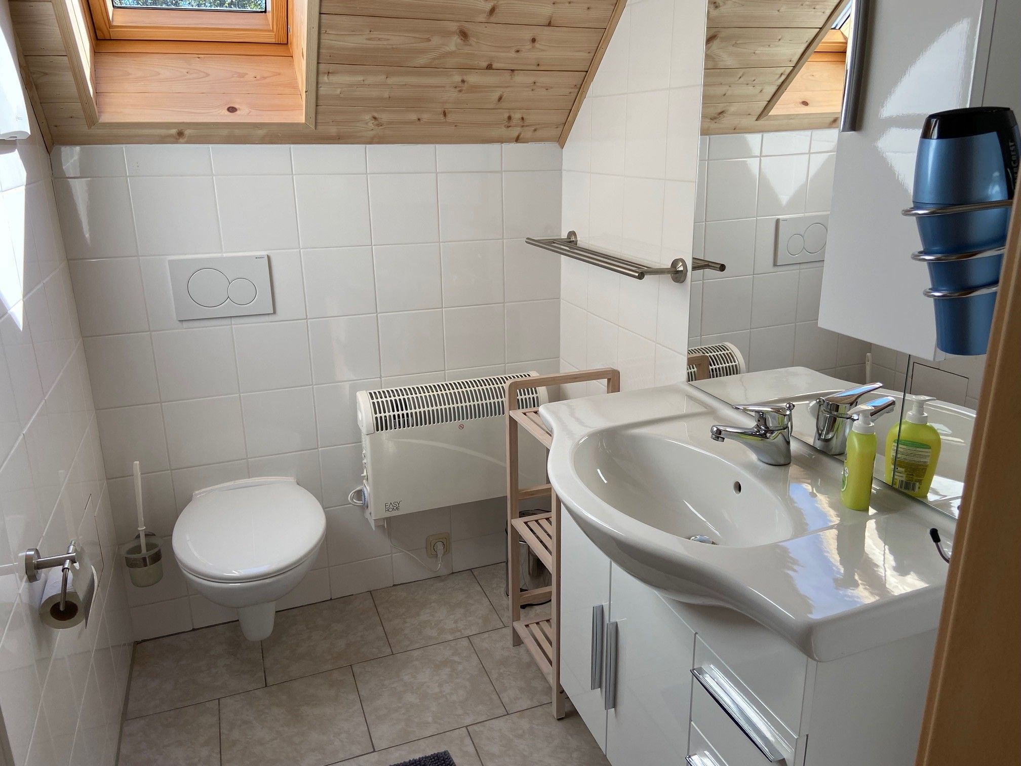 Modernes Badezimmer mit Dachfenster, Waschbecken, Toilette und Handtuchhalter.