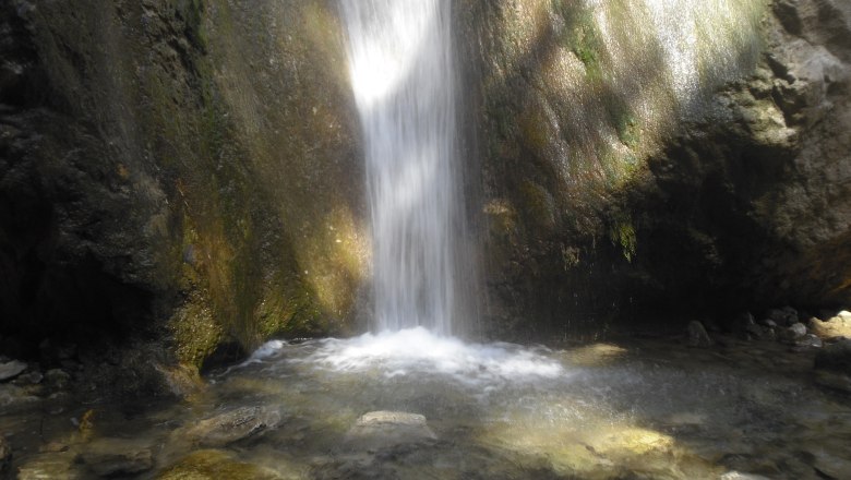 Wasserfall in einer felsigen Umgebung mit klarem Wasserbecken.